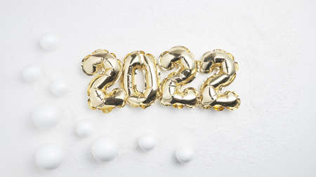 golden inflatable numbers 2022 on a background of white snow and white snow ballsの写真素材