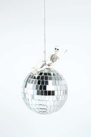 decorative skeleton figurine halloween decoration sitting astride a disco ball. Halloween partyの写真素材