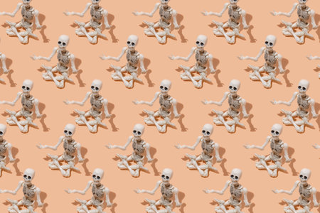 A pattern of skeletons sitting in a lotus position on a beige background. Human skeletons doing yoga, meditating.の写真素材