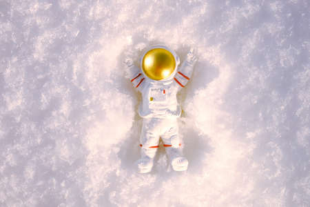 a small decorative figurine of an astronaut with arms raised up lies in the snow and makes a snow...