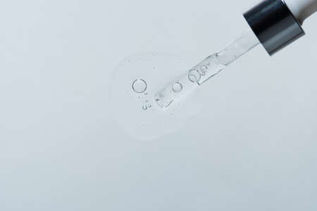 A drop of facial skin care product with a pipette and bubbles on a white background. Anti-aging...