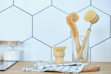 eco-friendly dishwashing brushes with organic bristles and a wooden handle next to a glass on the kitchen table. The concept of minimum consumption, zero-waistの写真素材