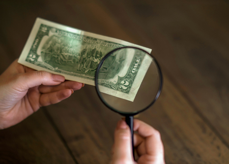 lucky dollar in hand through a magnifying glassの写真素材