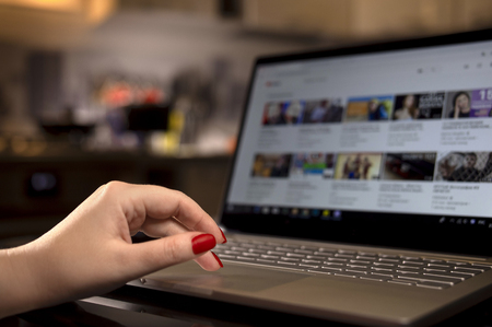 Womans hands with a bright manicure on a laptop keyboard in the evening at homeの写真素材