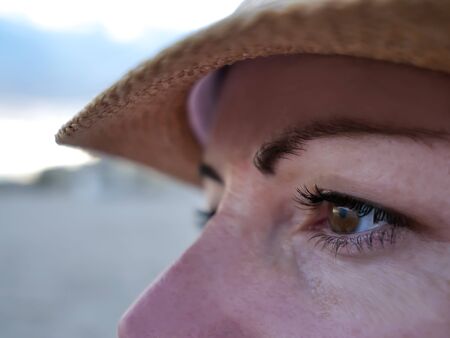 Portrait of a young woman in a hat looking to the side, close-up