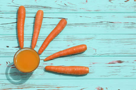 glass of fresh carrot juice on blue wooden background with copy spaceの写真素材