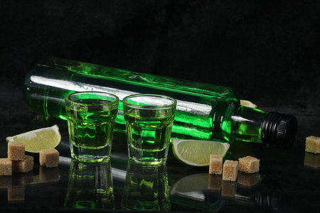 green absinthe drink on the black background with sugar and limeの写真素材
