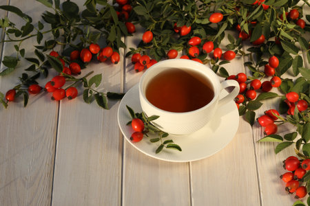 Cup of tea with rose berries on a white wooden backgroundの写真素材