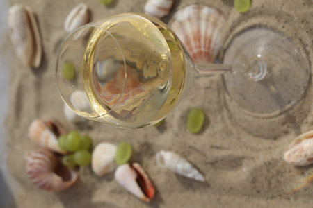 glass of white wine on sand as background with shellsの写真素材