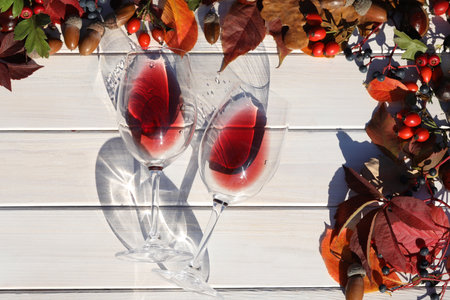 two glasses of red wine on wooden background with autumn leavesの写真素材