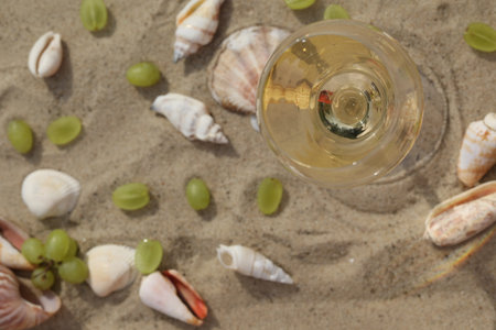 glass of white wine on sand as background with shellsの写真素材