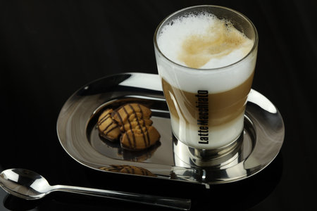 A glass of latte macchiato on a plate with a plate of cookies.の写真素材