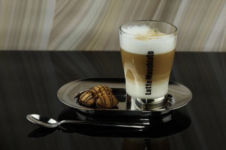 A glass of latte macchiato on a plate with a plate of cookies.の写真素材