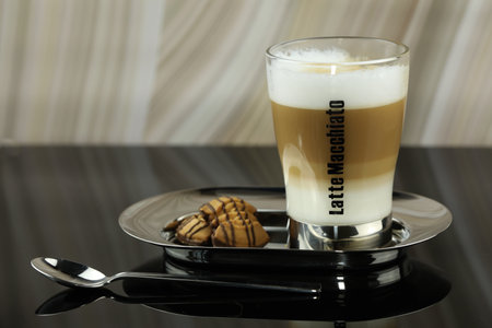 A glass of latte macchiato on a plate with a plate of cookies.の写真素材