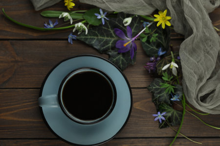 brown wooden background with spring flowers, leaves and coffeeの写真素材
