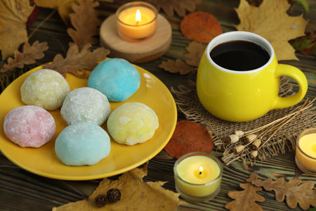 Colorful japanese sweets daifuku or mochi. Sweets close up on the plate with autumn leaves background and candles and coffeeの写真素材