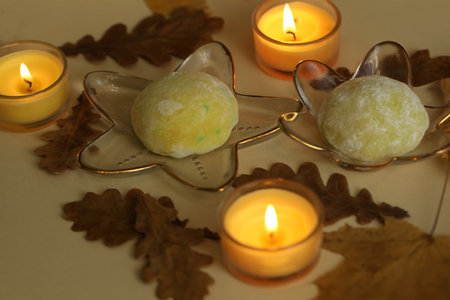 Colorful japanese sweets daifuku or mochi. Sweets close up on the plate with autumn leaves background and candlesの写真素材