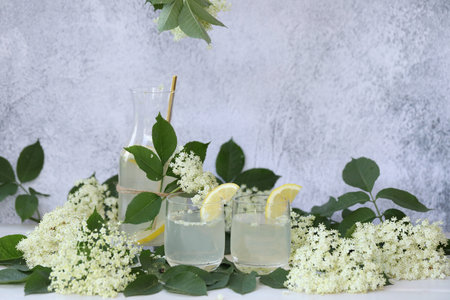 Glass and bottle of lemonade with elder flowers. On light gray background with copy spaceの写真素材