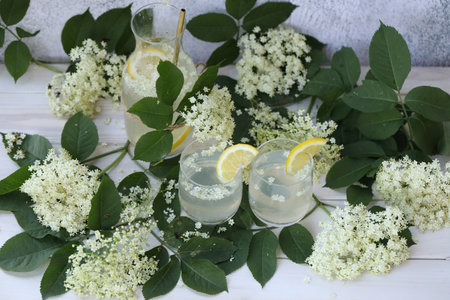 Glass and bottle of lemonade with elder flowers. On light gray background with copy spaceの写真素材