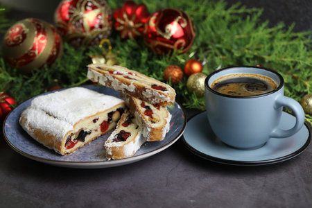 Sliced Chrismas stollen with powdered sugar and christmas decoration and cup of coffeeの写真素材