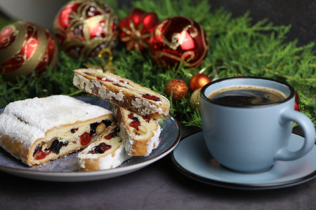 Sliced Chrismas stollen with powdered sugar and christmas decoration and cup of coffeeの写真素材