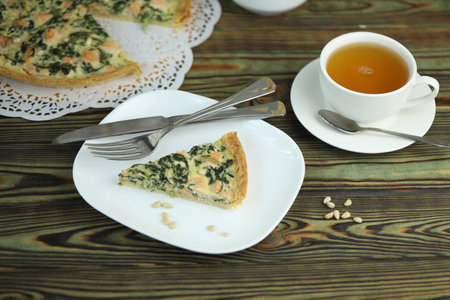 Delicious Quiche pie with salmon fish and pine nuts filling. Breakfast with quiche and cup of teaの写真素材