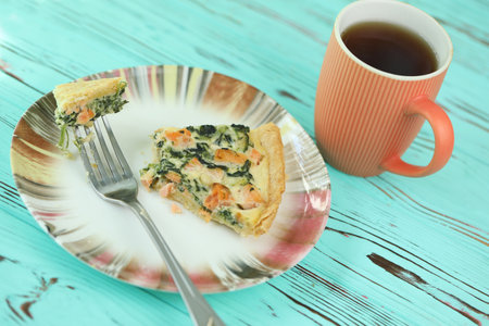 Delicious Quiche pie with salmon fish and pine nuts filling. Breakfast with quiche and cup of coffeeの写真素材