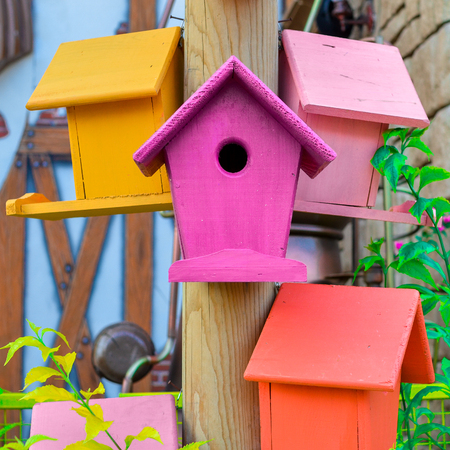 Multicolored nesting boxes birdhouses closeup outdoor with a part of house stone wall on the backgroundの写真素材