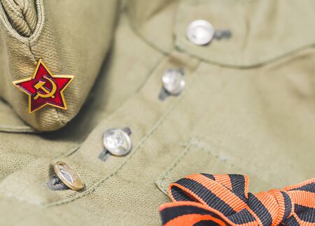 Closeup of forage cap with Red Army star and St. George ribbon lying on Soviet army military tunic...