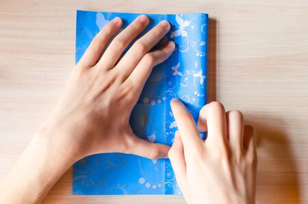 Girl's hands making origami blue dress from butterfly printed paper.の写真素材