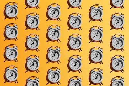 White retro alarm clock pattern on orange yellow background. Creative minimal time, school, business, morning, deadline concept. Top view, flatlay, layout.の写真素材
