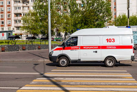 Moscow, Russia - May 22, 2020: coronavirus global pandemic recovery, russian ambulance car on the city road, crosswalk. Side view. Inscription on a car, translation: ambulance, 103.のeditorial素材