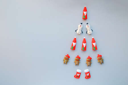 Creative walking Christmas tree made of New Year symbols decorations on grey background. Santa, snowman, gingerbread man, snow boot on Holiday card. Minimal concept, flat lay, copy space, top view.の写真素材