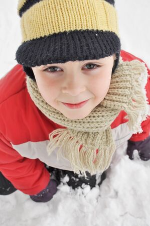 Portrait of a cute boy sitting in the snow の写真素材