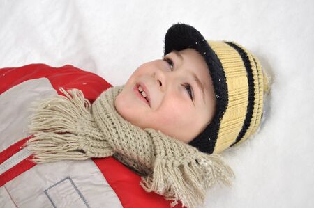 Portrait of a boy lying in the snow の写真素材