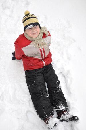 Portrait of a boy sitting in the snow の写真素材