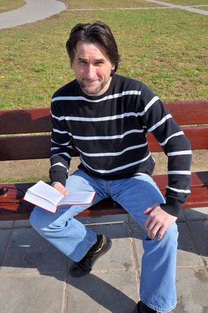 Man with book sitting on a benchの写真素材