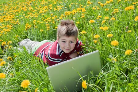 Boy with laptop computer lying on the grass