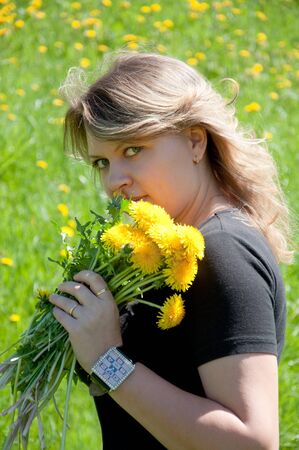 Portrait of a young girl on the lawn with a bouquet of dandelionsの写真素材