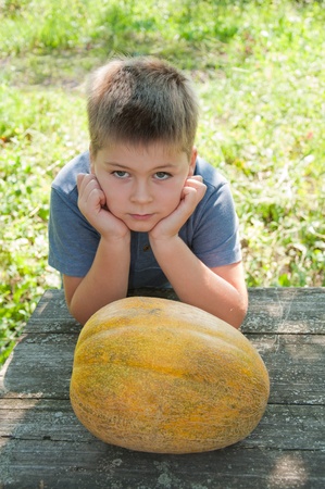 A boy with a large melon in his handsの写真素材