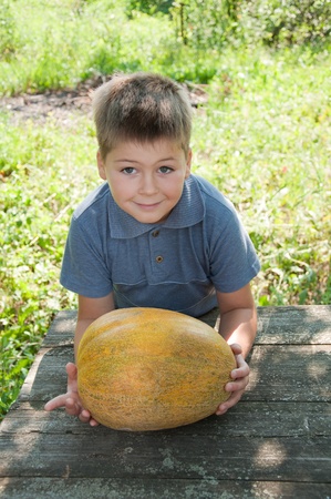 A boy with a large melon in his handsの写真素材