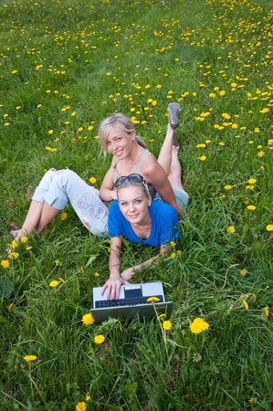 Two female students with a laptop in the parkの写真素材