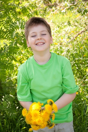 A boy with a bouquet of dandelions in the parkの写真素材