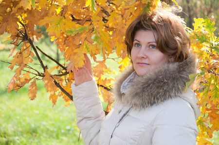 Beautiful young woman in autumn park with the leavesの写真素材