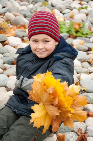 The Boy in the autumn park with a bunch of maple leavesの写真素材
