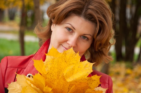 Woman in autumn park with a bouquet of maple leavesの写真素材