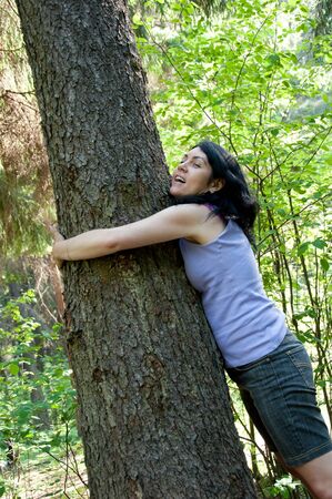 A beautiful middle-aged woman in a forest near an old treeの写真素材