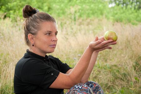 Middle-aged woman with an apple in his handの写真素材