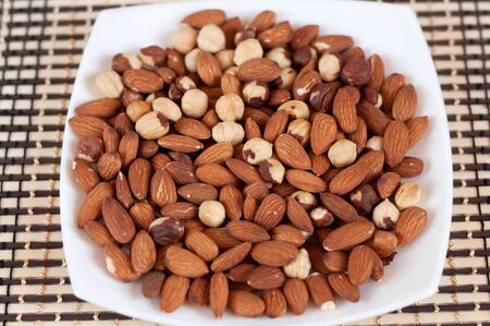 Roasted almonds and hazelnuts on a plateの写真素材
