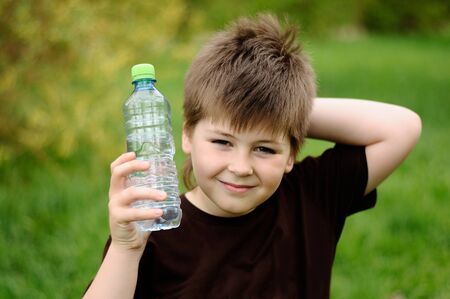 A boy with a bottle of water in natureの写真素材